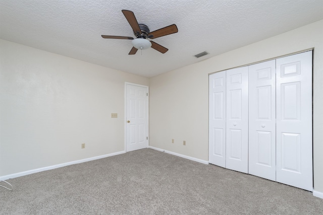 unfurnished bedroom with ceiling fan, light carpet, and a textured ceiling