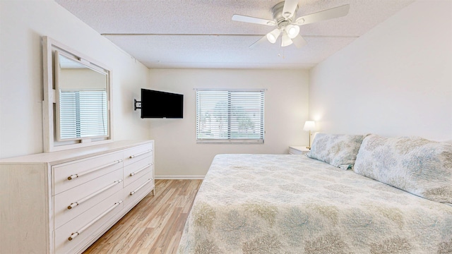 bedroom with ceiling fan, light hardwood / wood-style floors, and a textured ceiling