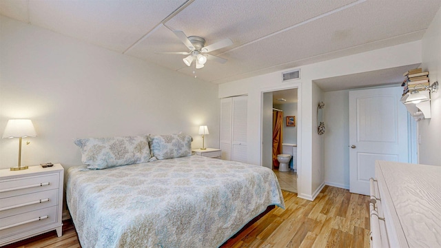 bedroom with light wood-type flooring, a closet, ceiling fan, and connected bathroom