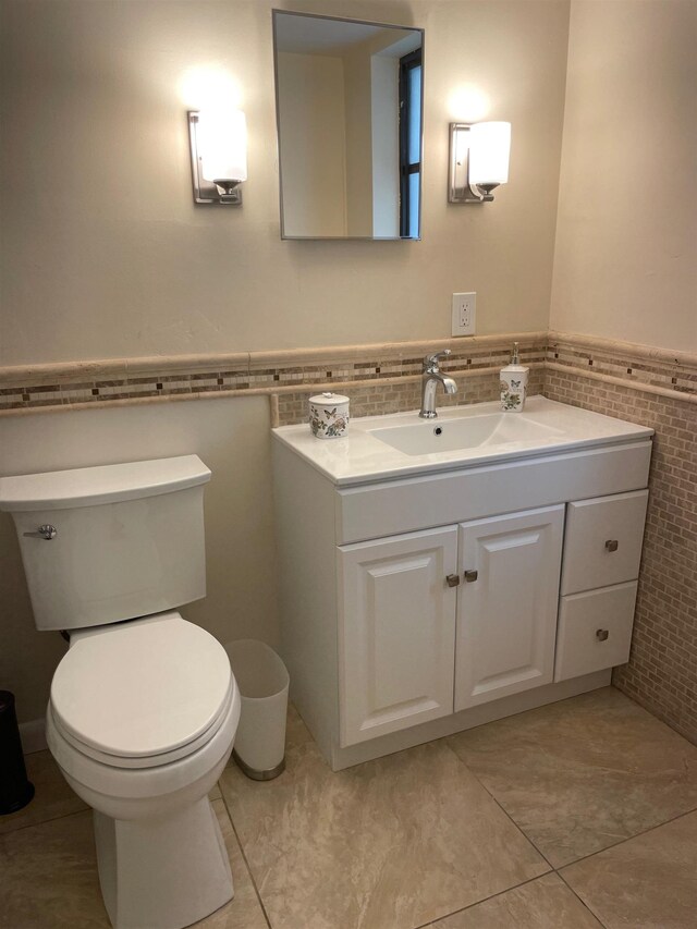 bathroom featuring tile patterned floors, vanity, toilet, and tile walls