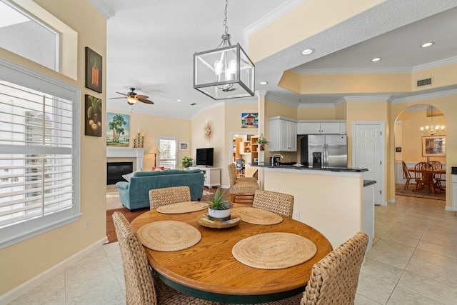 dining room with light tile patterned floors, crown molding, and ceiling fan with notable chandelier