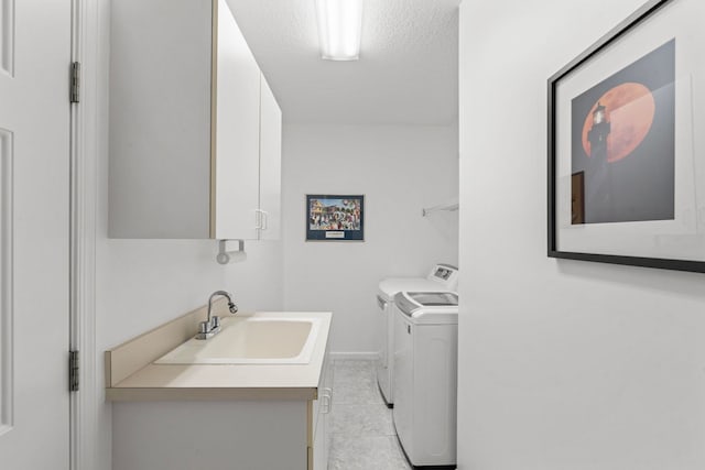 laundry area featuring cabinets, sink, washer and dryer, and a textured ceiling