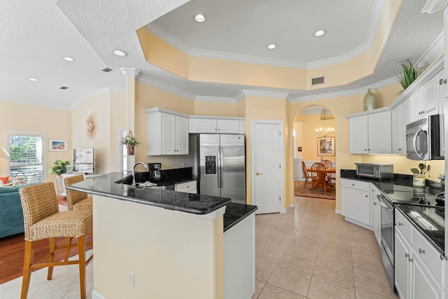 kitchen with white cabinetry, appliances with stainless steel finishes, a tray ceiling, and kitchen peninsula