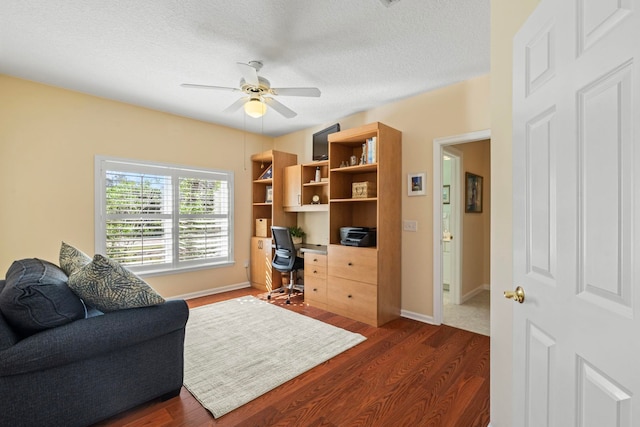 office area with ceiling fan, dark hardwood / wood-style flooring, and a textured ceiling