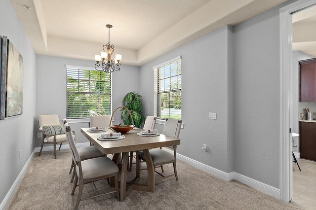 175 Laterra Links Cir Unit 101, Saint Augustine, FL 32092 - dining room featuring a tray ceiling, an inviting chandelier, baseboards, and plenty of natural light