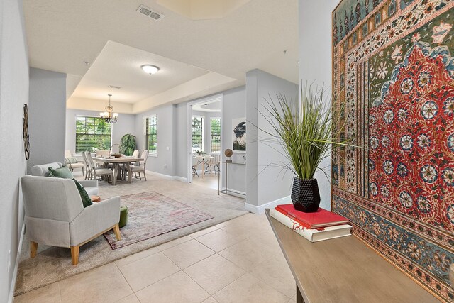 175 Laterra Links Cir Unit 101, Saint Augustine, FL 32092 - interior space featuring light tile patterned floors, visible vents, baseboards, a raised ceiling, and a chandelier