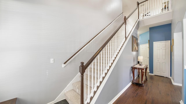 stairs with baseboards, a towering ceiling, and wood finished floors