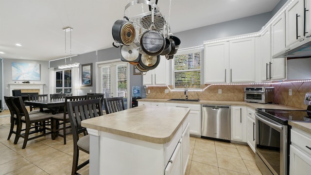 kitchen with light tile patterned floors, a sink, decorative backsplash, light countertops, and appliances with stainless steel finishes