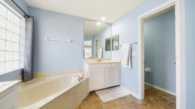 bathroom featuring tile patterned flooring, vanity, a bath, and baseboards