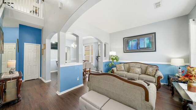 living room featuring arched walkways, visible vents, dark wood-type flooring, and baseboards