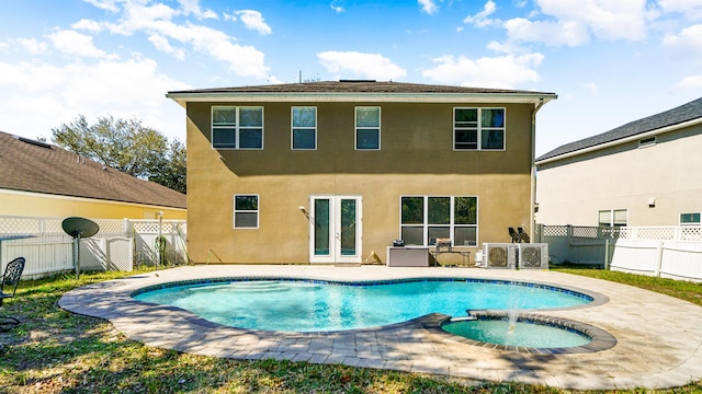 rear view of property with stucco siding, a patio, a fenced backyard, french doors, and an in ground hot tub