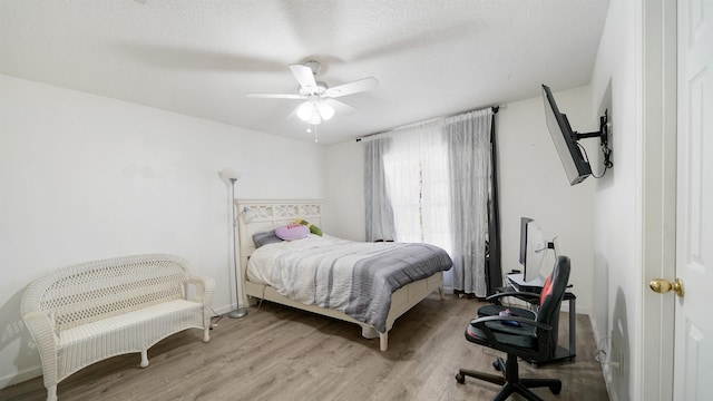 bedroom featuring ceiling fan, a textured ceiling, and wood finished floors