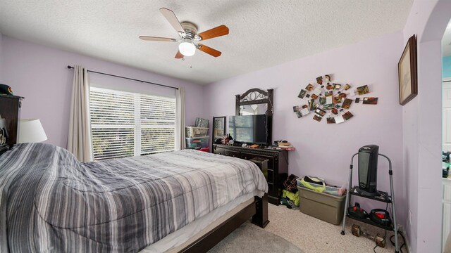 carpeted bedroom featuring a textured ceiling and a ceiling fan