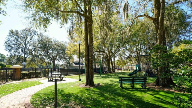 surrounding community with playground community, a lawn, and fence