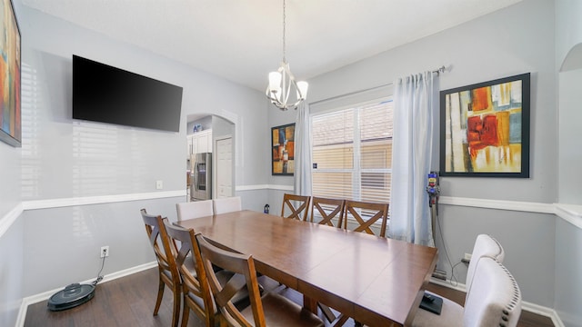 dining room featuring arched walkways, an inviting chandelier, baseboards, and wood finished floors