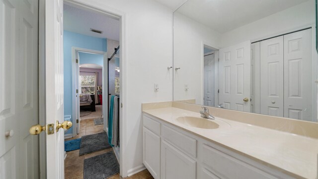 full bath with vanity, ensuite bathroom, visible vents, and a closet