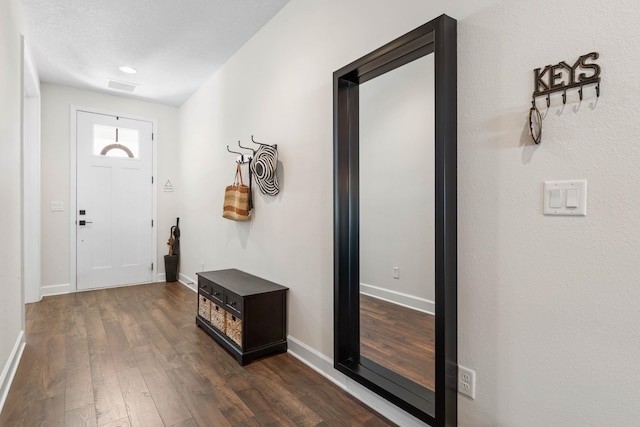 entrance foyer with baseboards, visible vents, and dark wood-type flooring