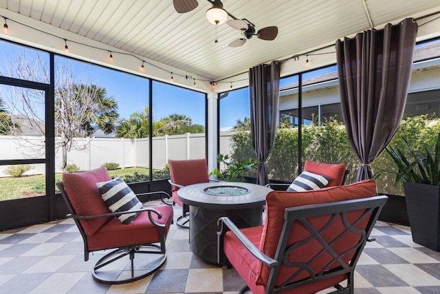 sunroom featuring rail lighting, plenty of natural light, and a ceiling fan