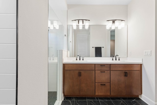 bathroom featuring double vanity, marble finish floor, a tile shower, and a sink