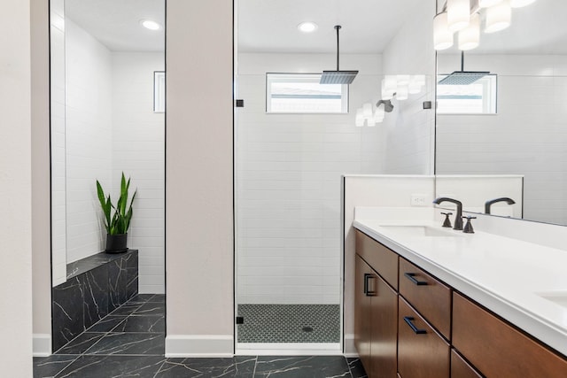 full bath featuring marble finish floor, plenty of natural light, walk in shower, and a sink