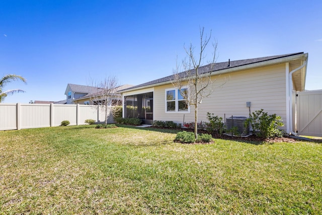 rear view of property with central AC unit, a lawn, a fenced backyard, and a sunroom