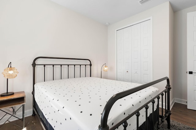 bedroom featuring visible vents, baseboards, dark wood finished floors, and a closet