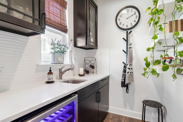 bar featuring wine cooler, indoor wet bar, dark wood finished floors, a sink, and baseboards