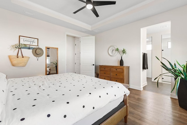 bedroom with ceiling fan, dark wood-type flooring, baseboards, ornamental molding, and a raised ceiling