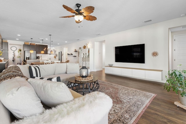 living area with visible vents, dark wood finished floors, and a textured ceiling