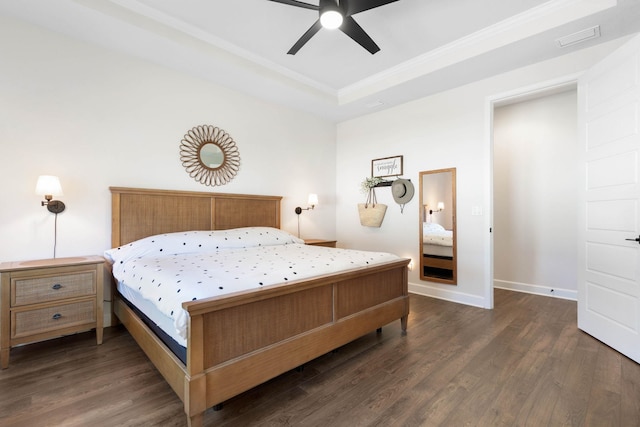 bedroom featuring a tray ceiling, dark wood finished floors, visible vents, and baseboards