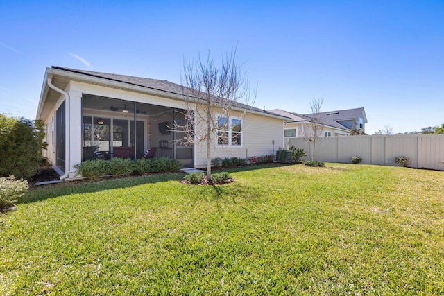 rear view of property featuring a yard, fence, and a sunroom