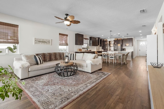 living room featuring visible vents, ceiling fan, a textured ceiling, and wood finished floors