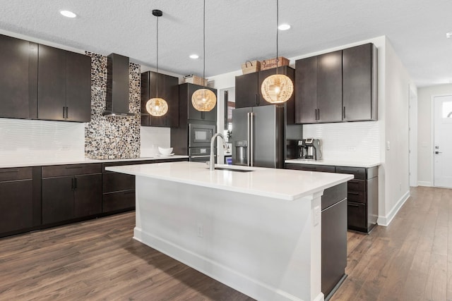 kitchen featuring high quality fridge, a sink, wall chimney exhaust hood, and dark wood-style floors