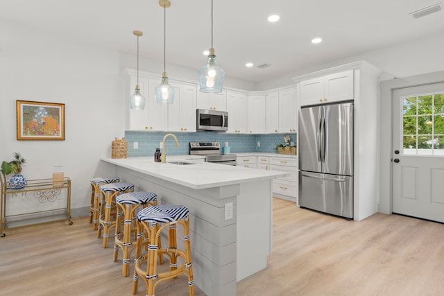 kitchen with a kitchen breakfast bar, sink, appliances with stainless steel finishes, white cabinetry, and kitchen peninsula