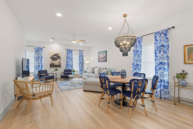 dining space with light hardwood / wood-style flooring and ceiling fan with notable chandelier