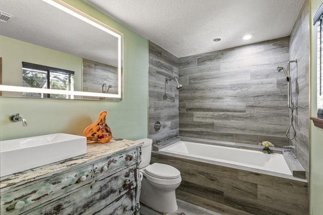 full bathroom with vanity, a textured ceiling, tiled shower / bath combo, hardwood / wood-style floors, and toilet