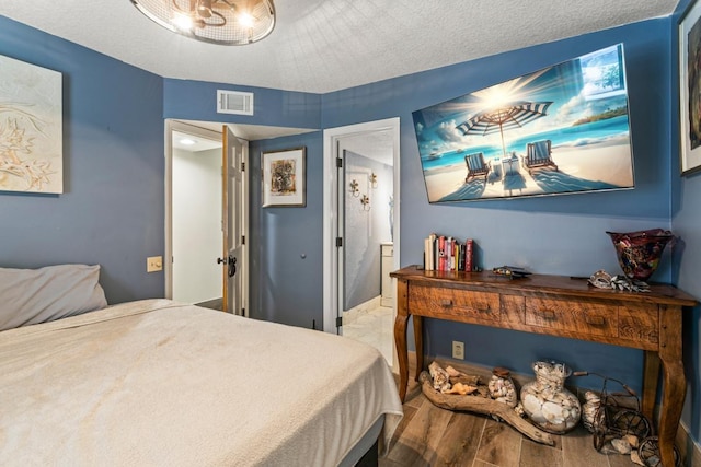 bedroom with a textured ceiling and hardwood / wood-style flooring