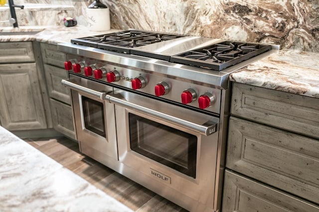 kitchen featuring dark hardwood / wood-style floors, double oven range, light stone countertops, and sink