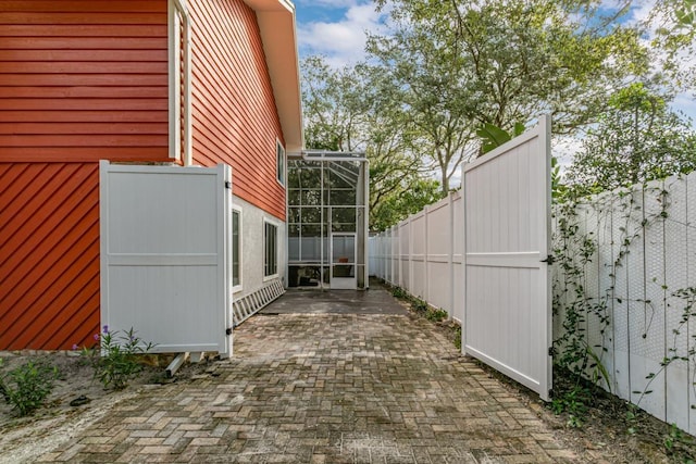 view of side of property with glass enclosure and a patio area