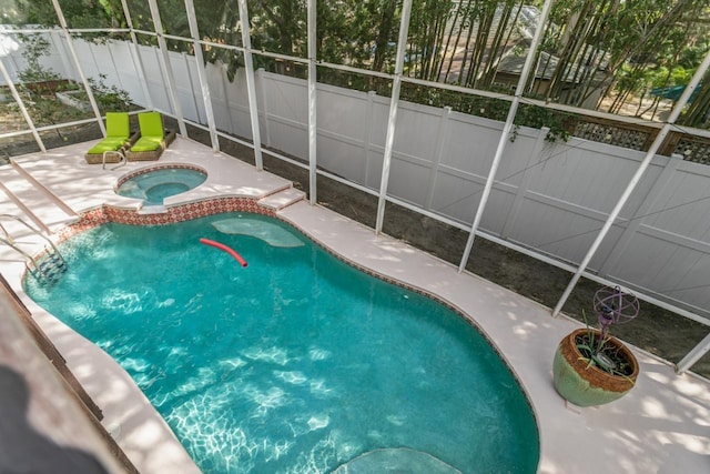 view of pool featuring an in ground hot tub, a patio, and glass enclosure