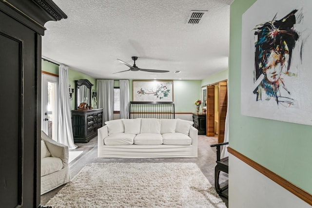 living room featuring ceiling fan, a textured ceiling, and light carpet