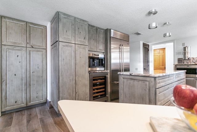 kitchen with a textured ceiling, dark hardwood / wood-style flooring, built in appliances, and beverage cooler