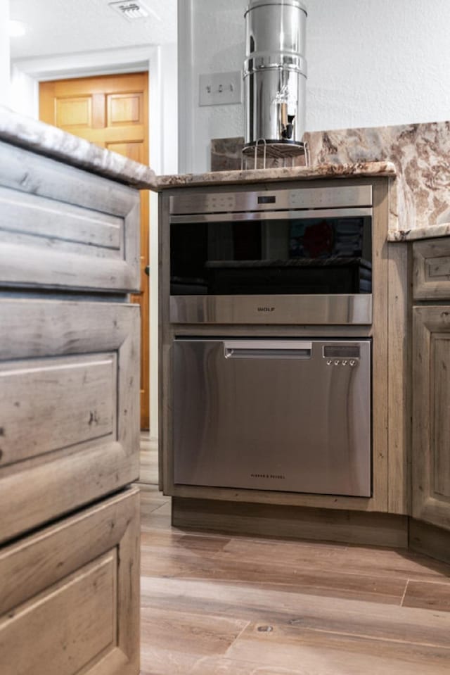 details with light hardwood / wood-style floors and stainless steel oven