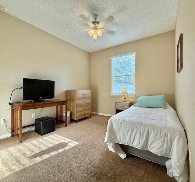 bedroom with carpet flooring, a textured ceiling, baseboards, and a ceiling fan