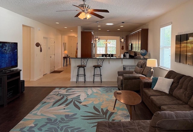 living room featuring a ceiling fan, a textured ceiling, dark wood finished floors, recessed lighting, and baseboards
