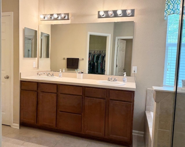 full bathroom with double vanity, tile patterned floors, a spacious closet, and a textured wall