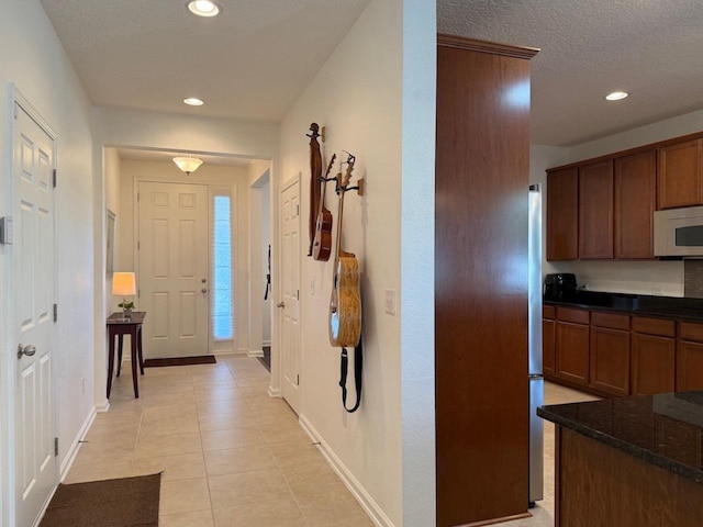 foyer with recessed lighting, baseboards, light tile patterned flooring, and a textured ceiling