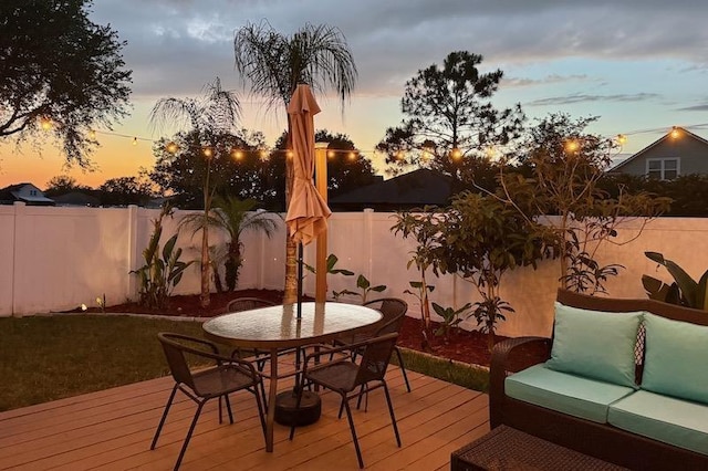 deck at dusk featuring outdoor dining area, a fenced backyard, and outdoor lounge area