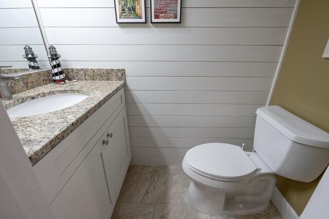 bathroom with wooden walls, vanity, and toilet