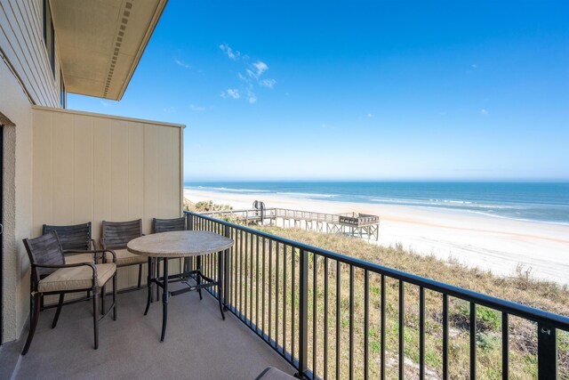 balcony with a water view and a view of the beach